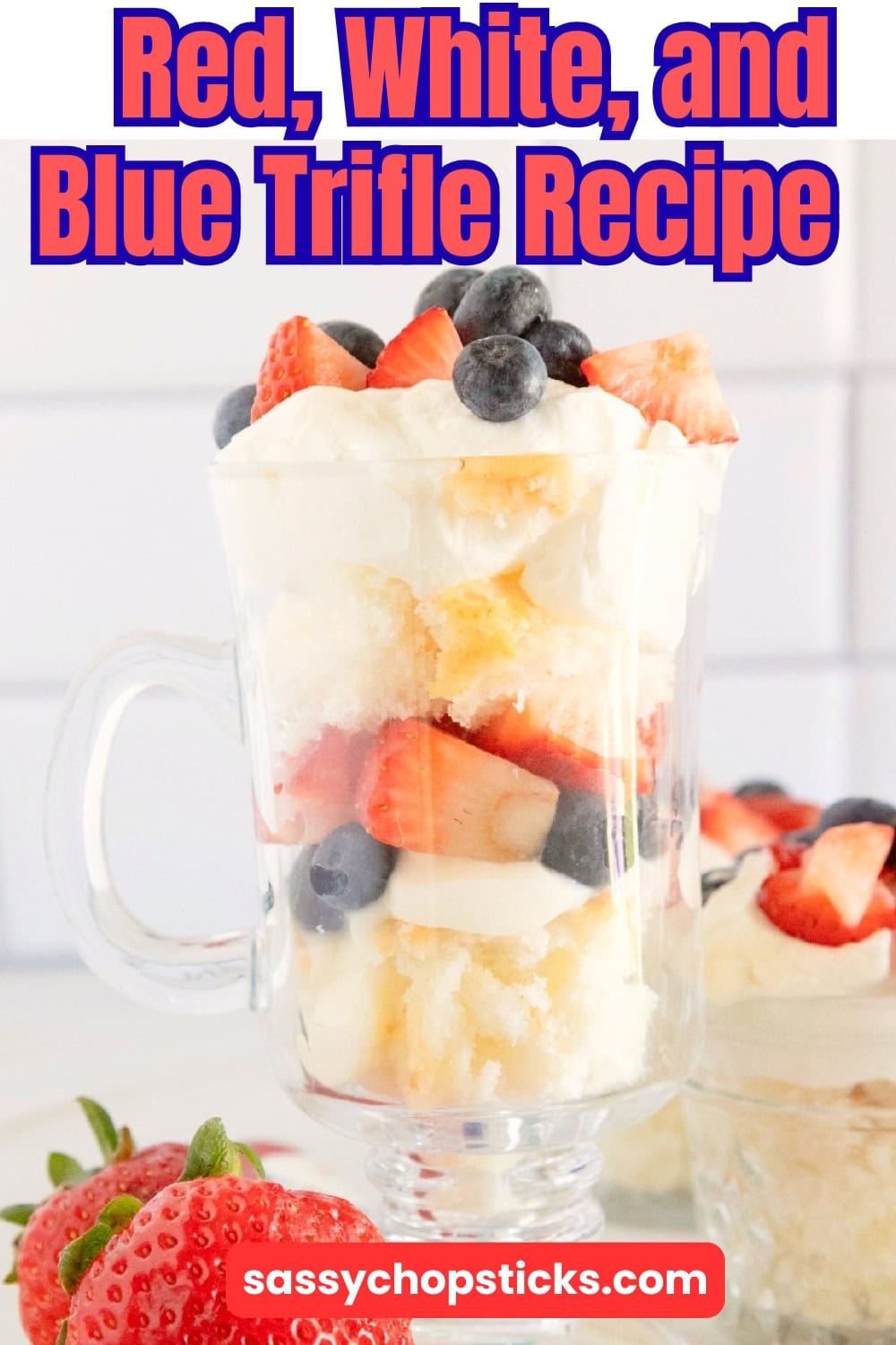 Red white and blue trifle layered with angel food cake, vanilla pudding, whipped topping, fresh strawberries, and blueberries in a glass mug.