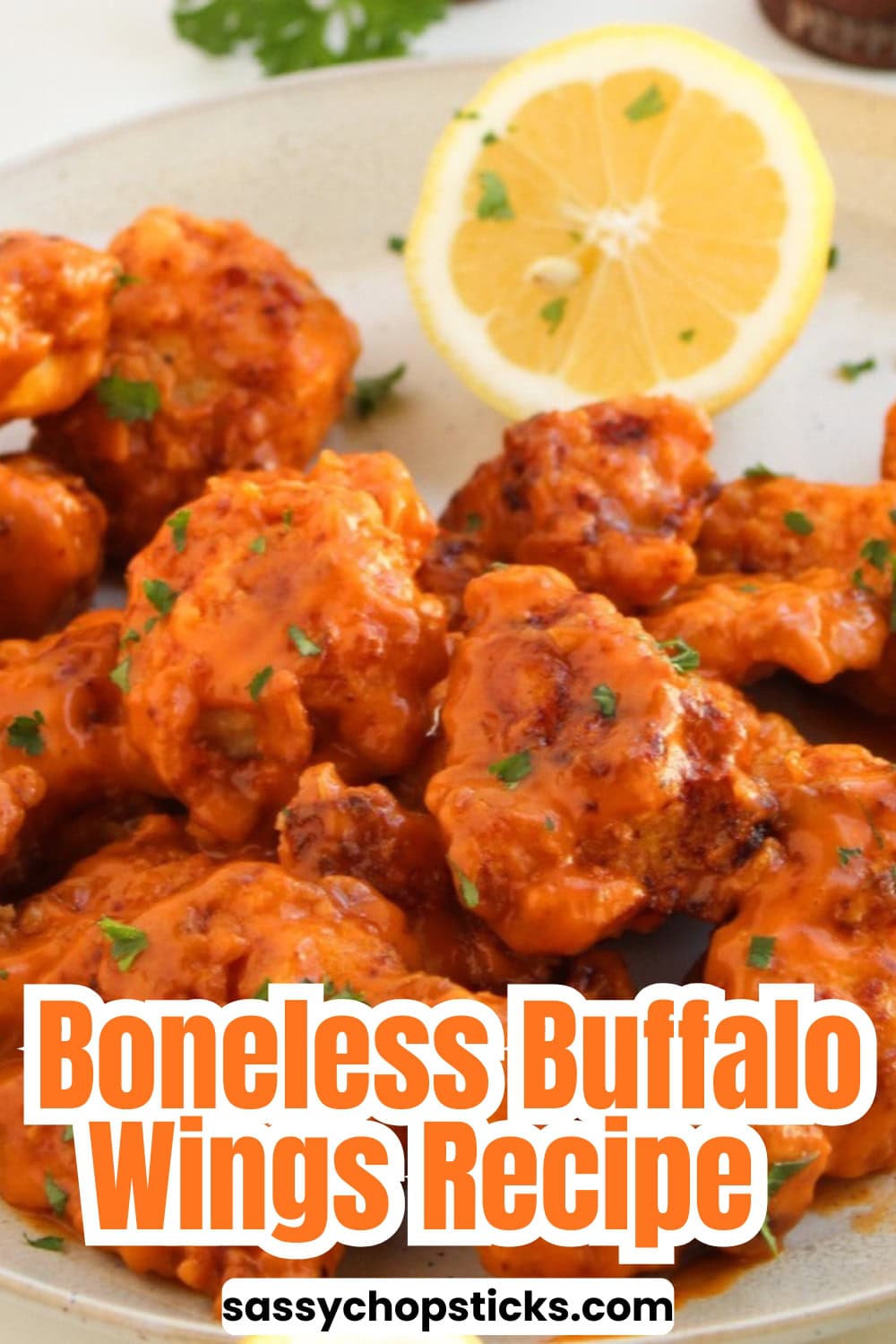 Boneless buffalo wings coated in spicy buffalo sauce with a lemon slice garnish on a serving plate.