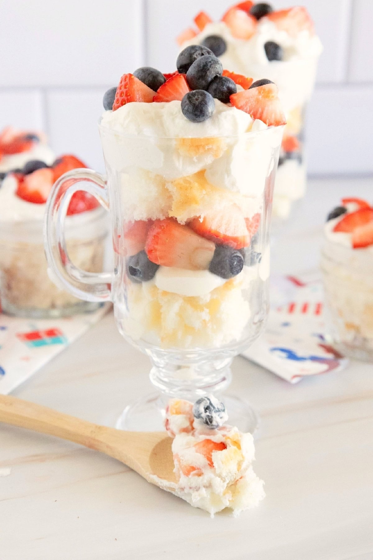 Close-up of a layered red, white, and blue trifle with angel food cake, whipped topping, strawberries, and blueberries.