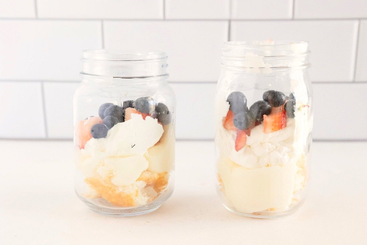 Fresh strawberries and blueberries are layered over pudding and whipped topping in individual trifle jars.