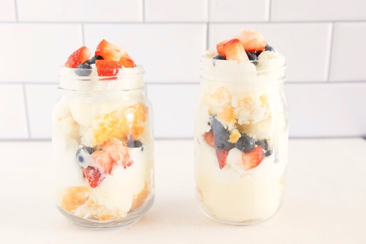 Additional layers of cake, pudding, whipped topping, strawberries, and blueberries added to complete the trifles.