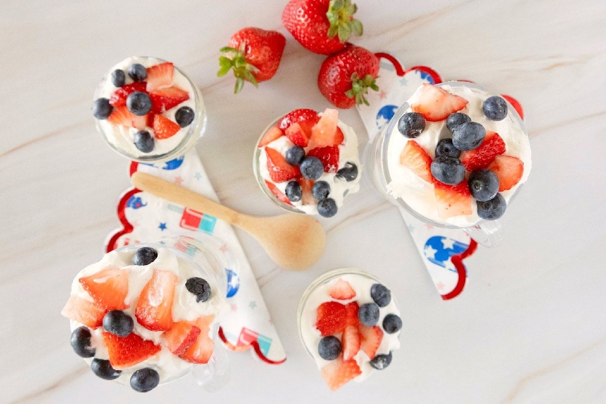 Overhead view of assembled red white and blue trifles topped with fresh strawberries and blueberries.