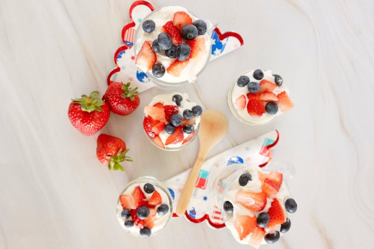 Top-down view of individual red white and blue trifles garnished with whipped topping, strawberries, and blueberries.