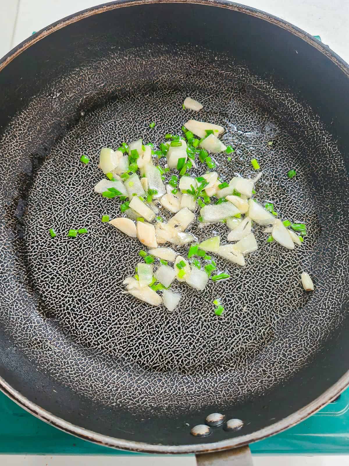 Garlic, diced onion, and green onions sautéing in a skillet for vegan kimchi fried rice.