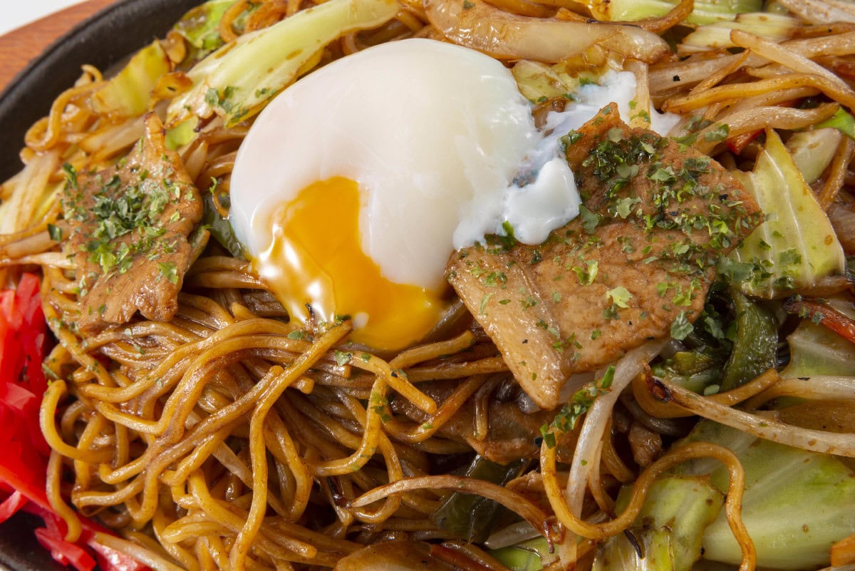 Japanese yaki soba noodles with vegetables, pork, and a soft egg.