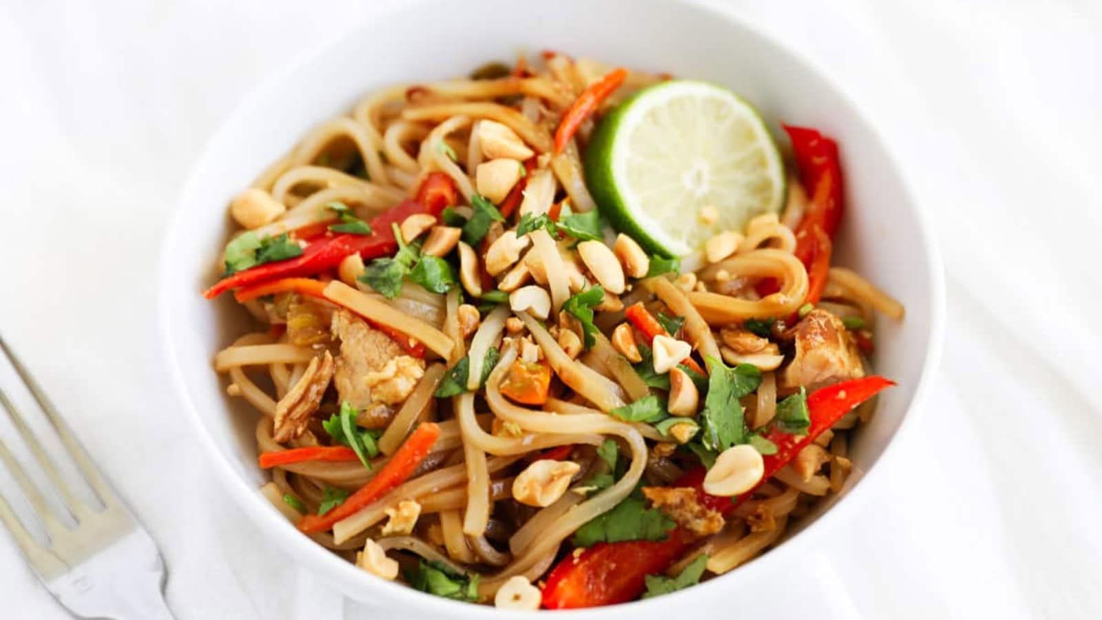 Rice noodles tossed with chicken, eggs, and fresh garnishes.