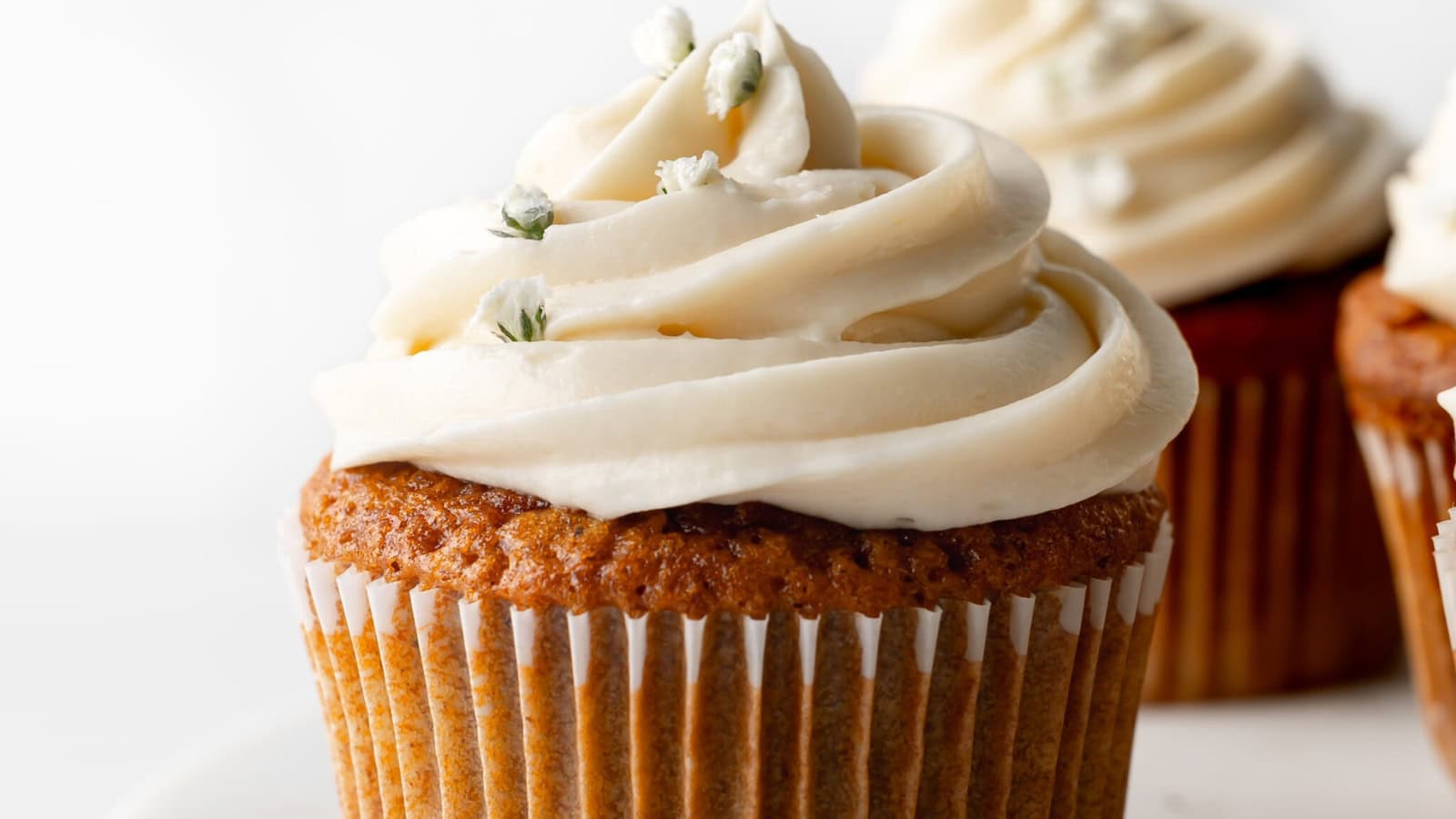 Gluten-free carrot cake cupcakes topped with creamy frosting.