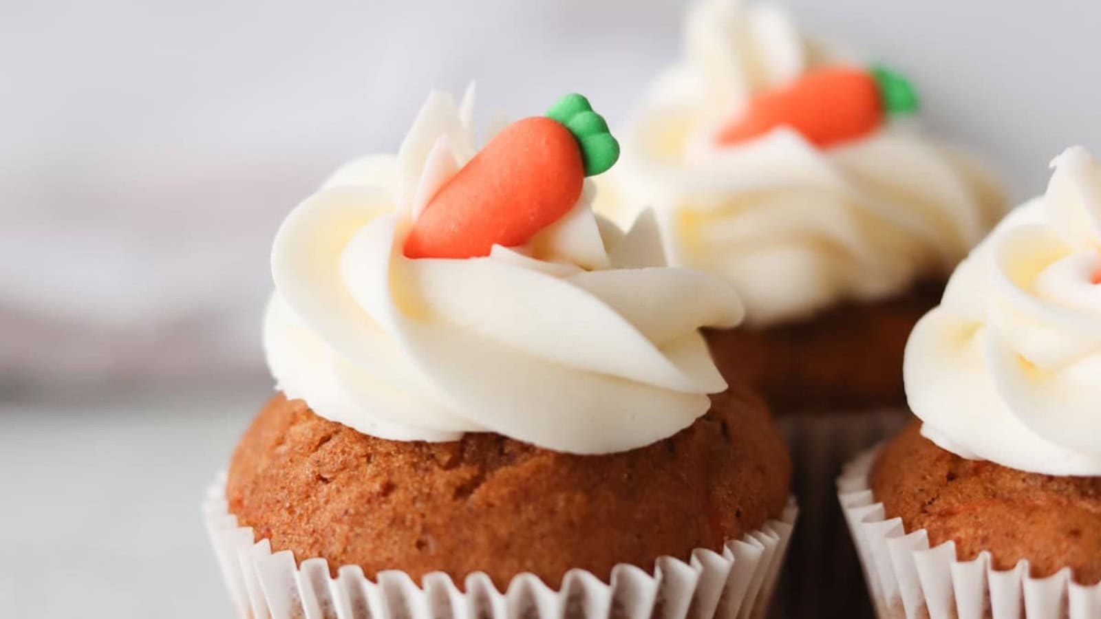 Soft gluten-free carrot cake cupcakes finished with cream cheese frosting.