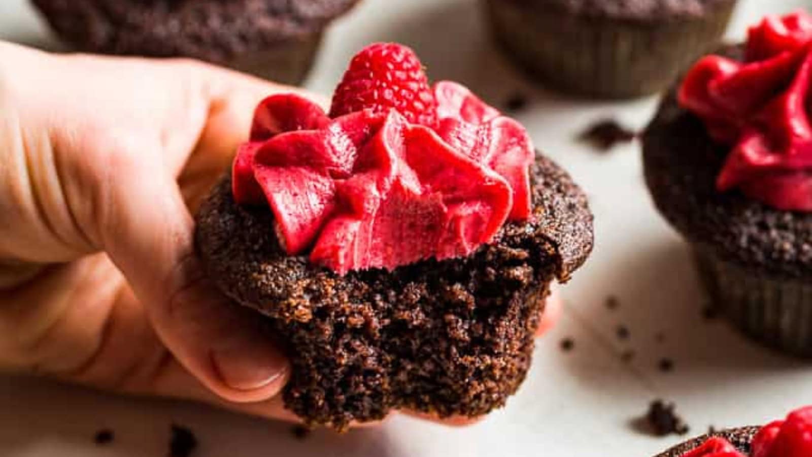 Gluten-free chocolate cupcakes topped with raspberry buttercream frosting.