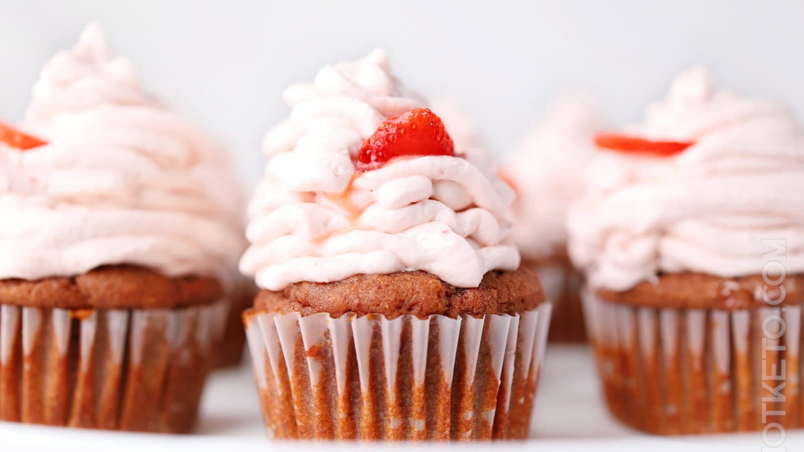 Strawberry cupcakes topped with smooth cream cheese frosting.
