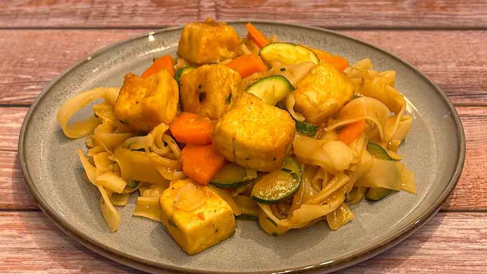 Rice noodles stir-fried with tofu, vegetables, and peanuts.