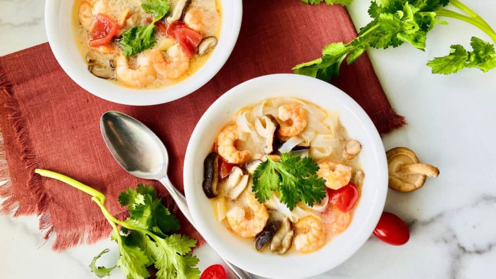 Spicy tom yum soup with noodles, herbs, and vegetables.