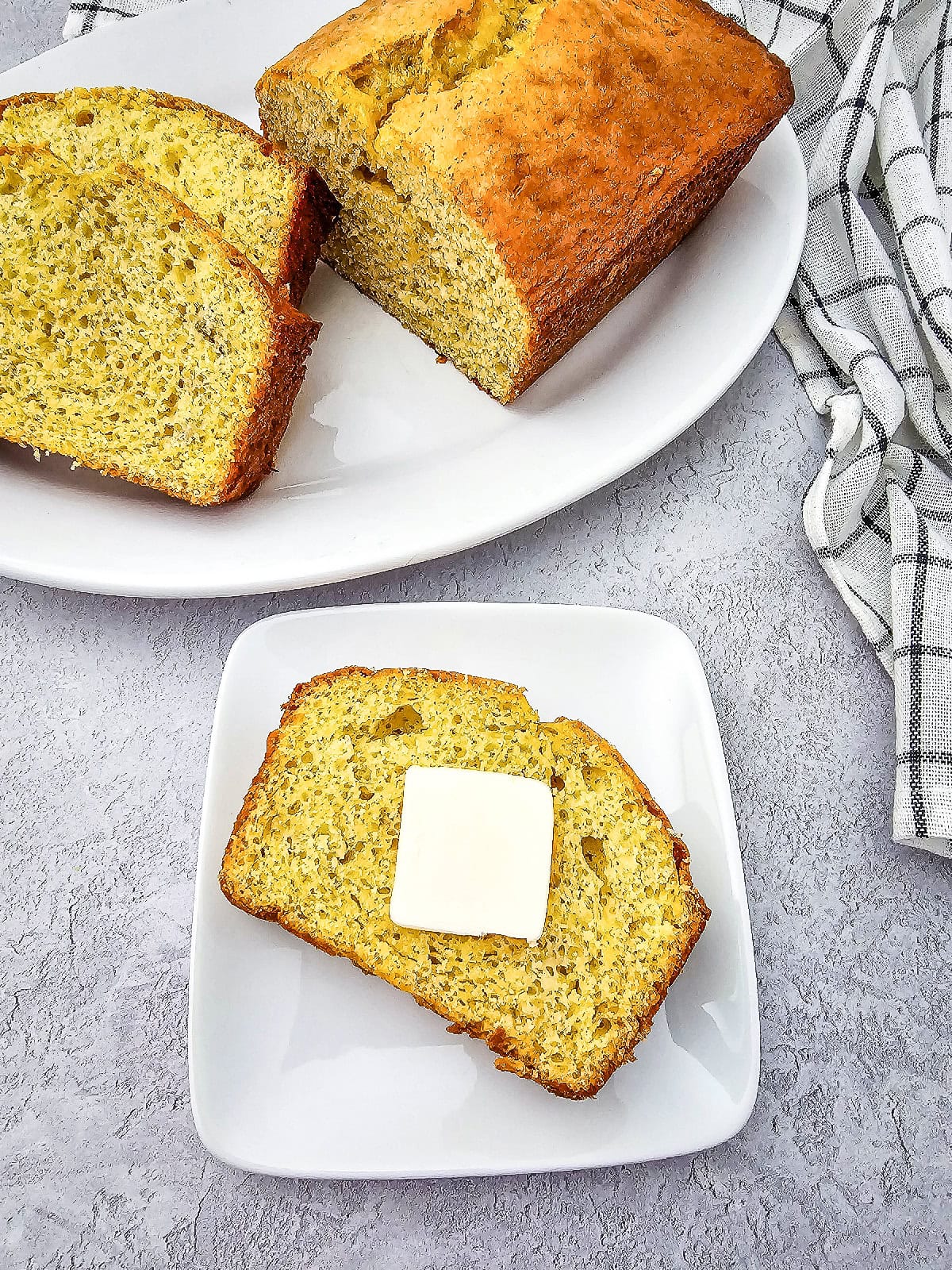 Banana bread made with yellow cake mix with a buttered slice served alongside the baked loaf.