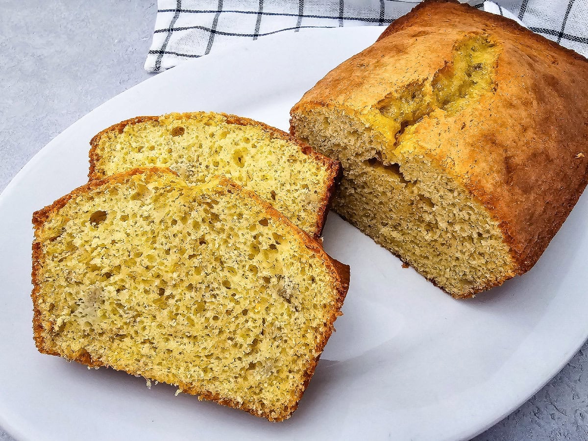 Sliced banana bread made with yellow cake mix served next to the remaining loaf on a white plate.