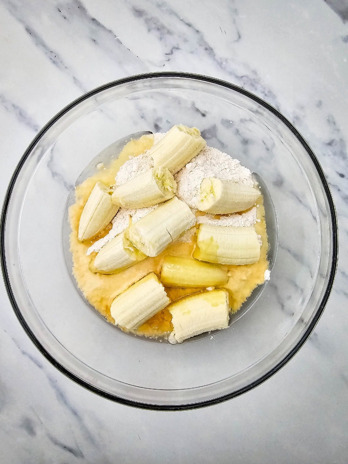 Banana chunks, yellow cake mix, and vegetable oil added to the mixing bowl for banana bread batter.