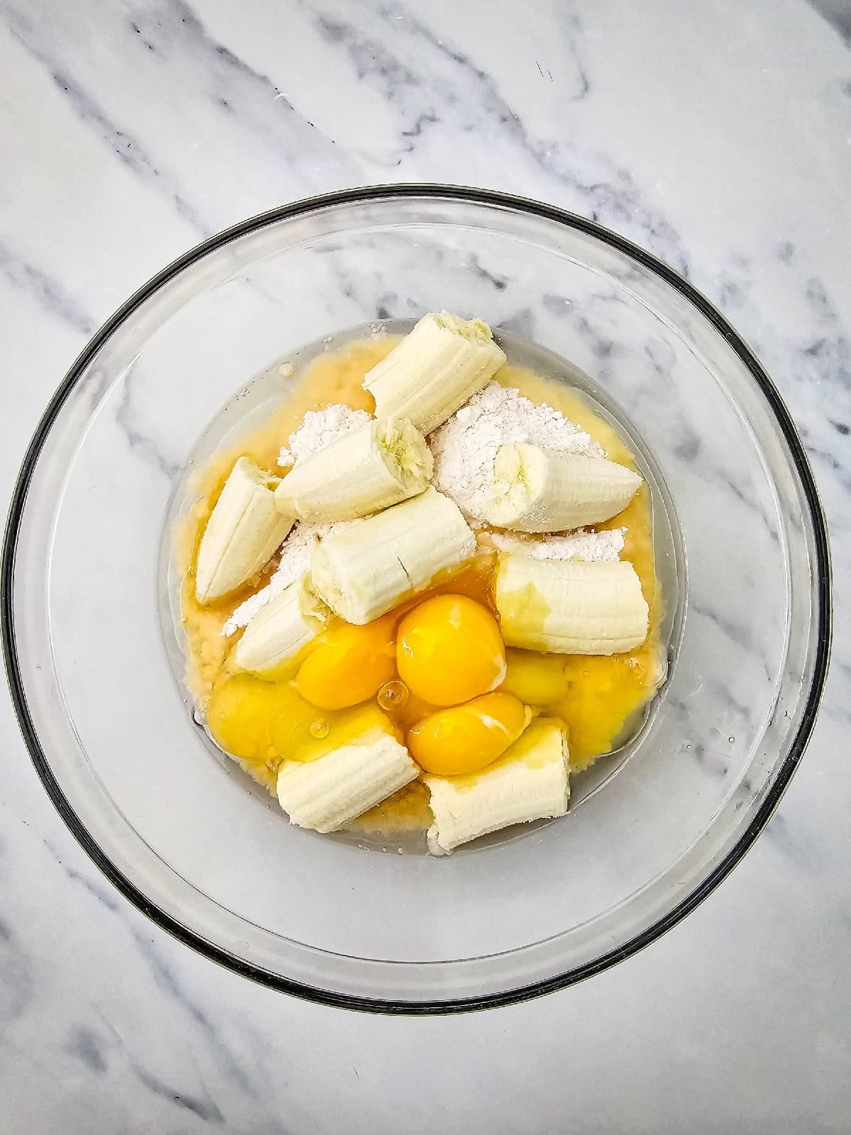 Eggs added to banana, yellow cake mix, and oil before mixing the banana bread batter.