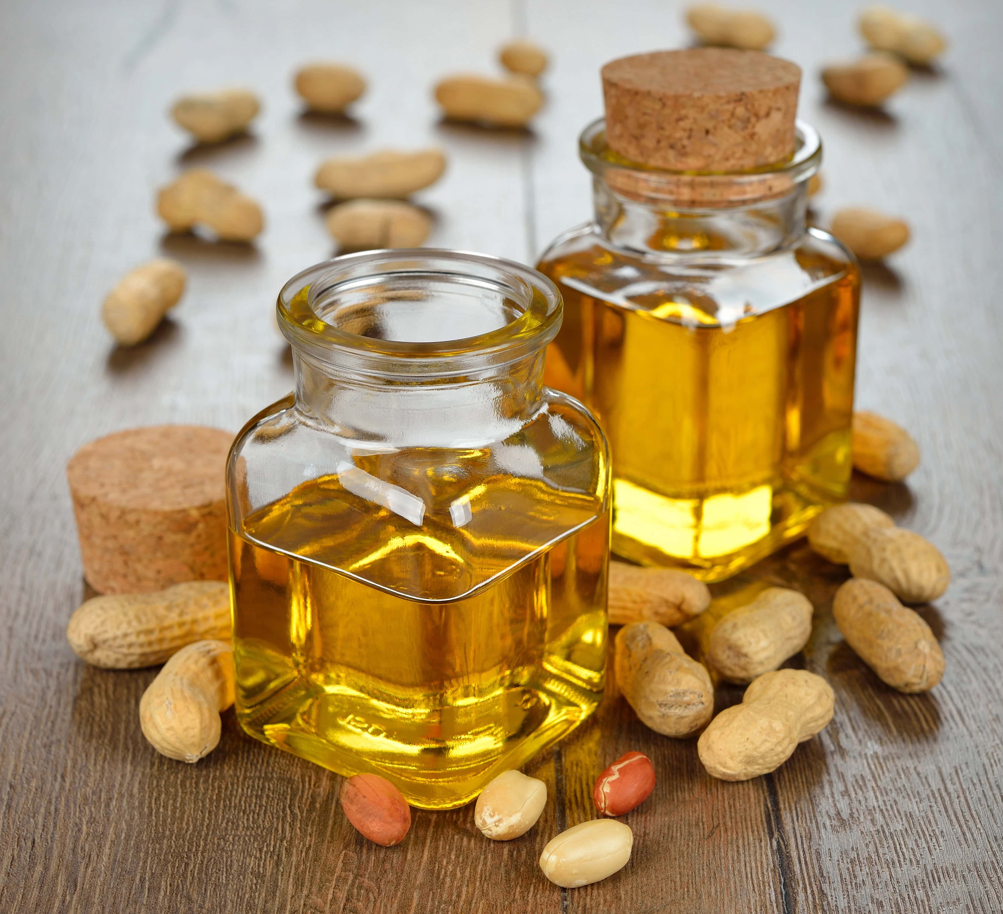 Peanut oil in glass bottles with whole peanuts, one of the best oils for stir fry.