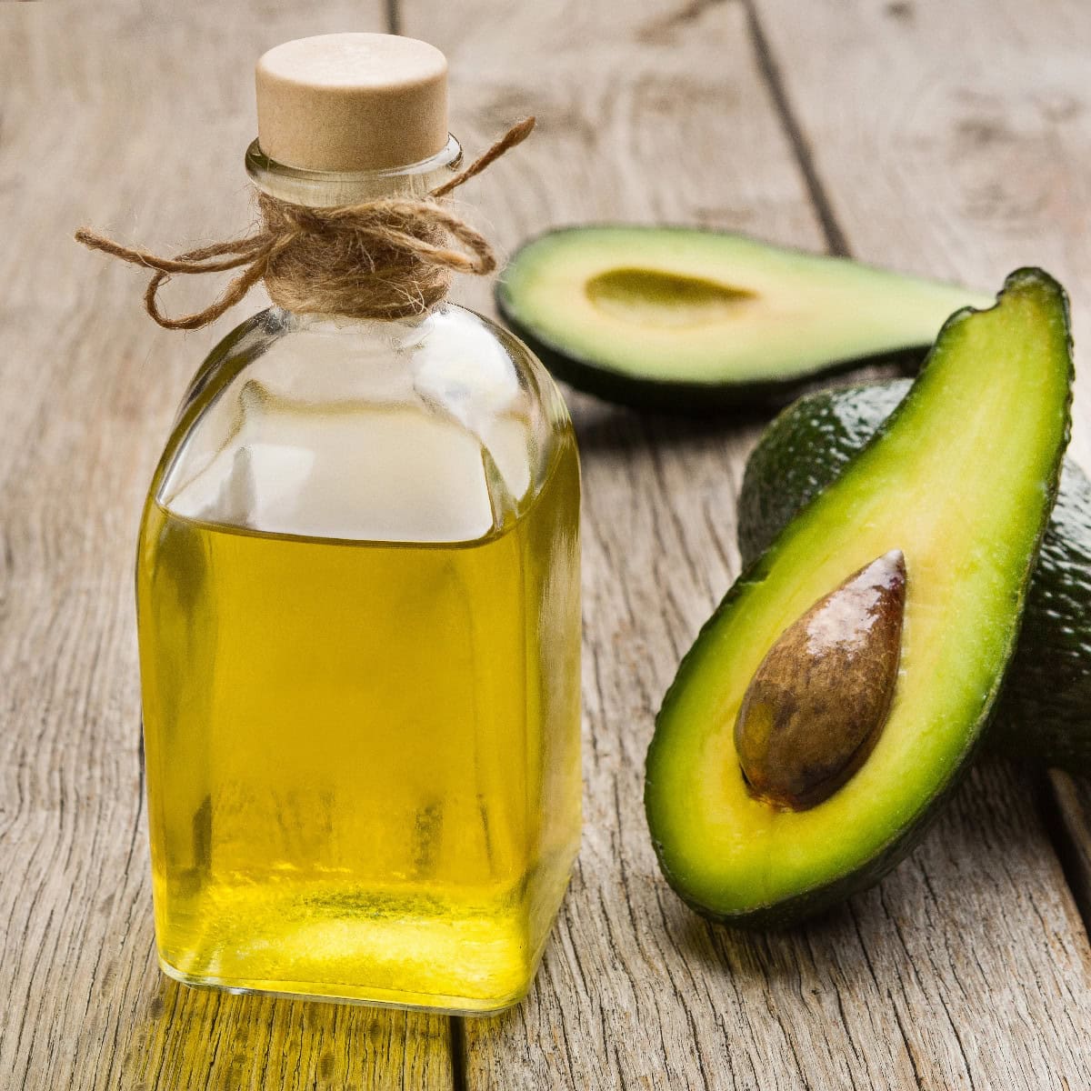 Avocado oil in a glass bottle with fresh avocados, an excellent oil for high-heat stir fry cooking.