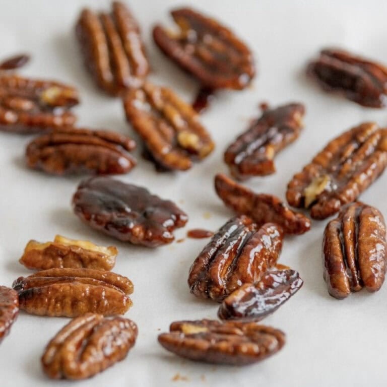 Perfectly toasted pecans with a golden brown color cooling on parchment paper.