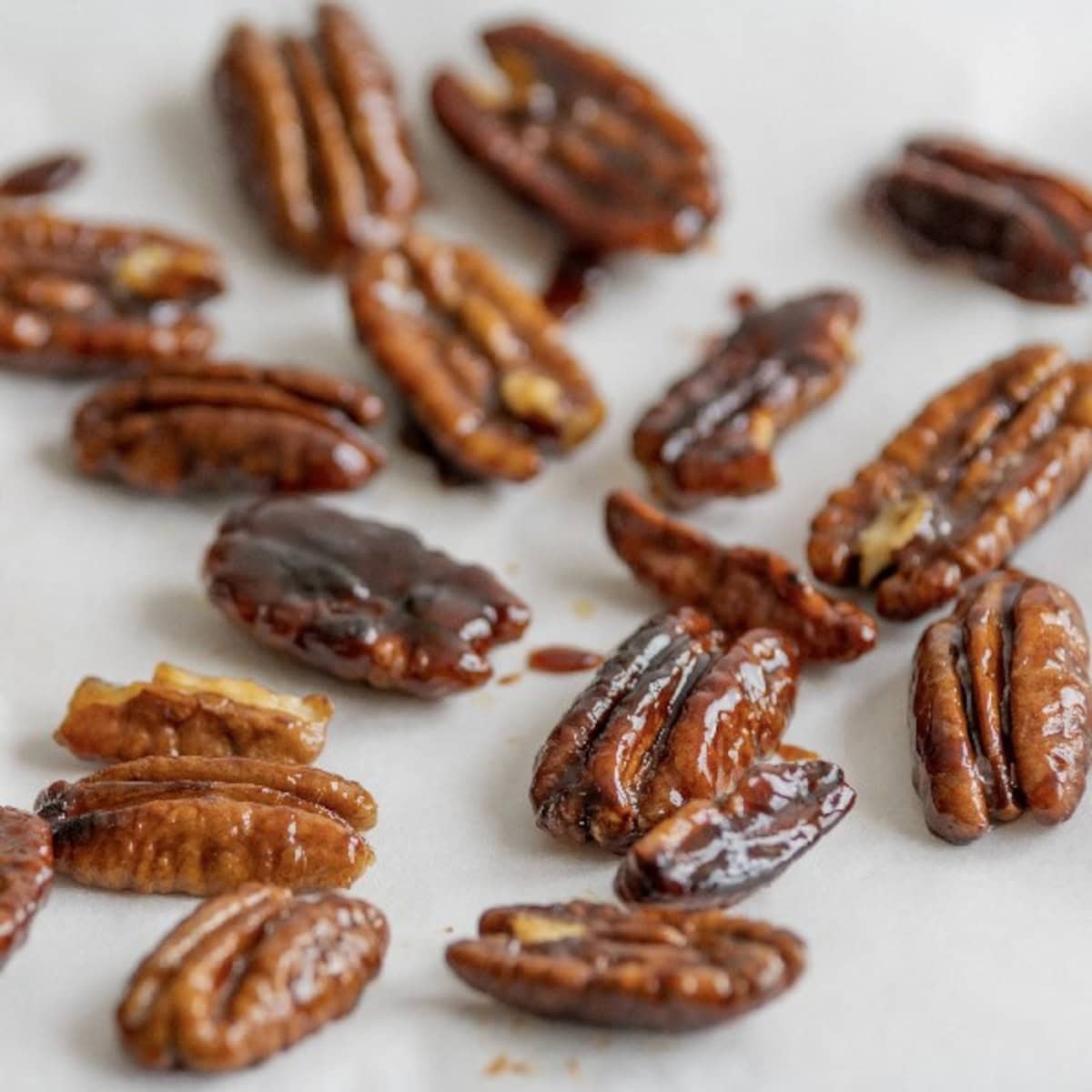 Perfectly toasted pecans with a golden brown color cooling on parchment paper.