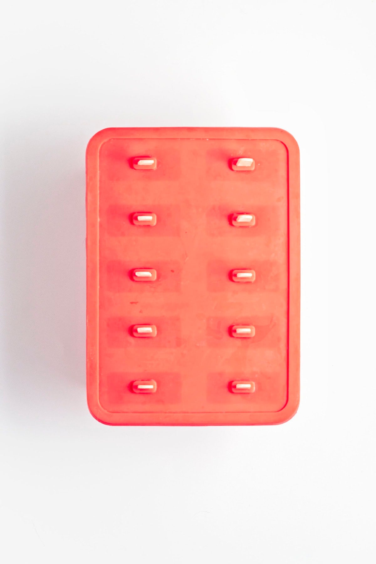 Silicone popsicle mold filled with layered matcha and strawberry mixtures before freezing.