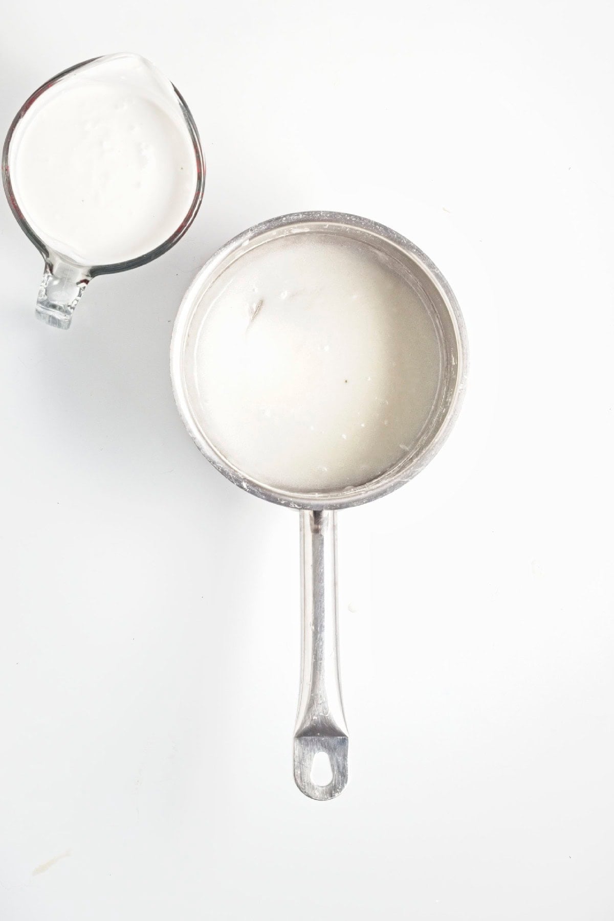 Coconut milk and cornstarch mixture cooking in a saucepan until thickened.