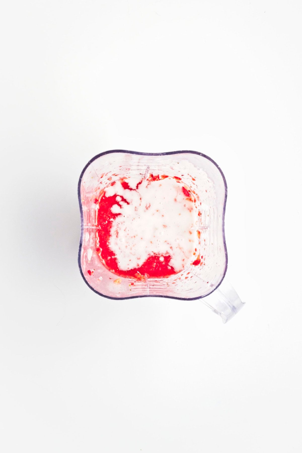 Coconut milk added to the blended strawberry puree before mixing.