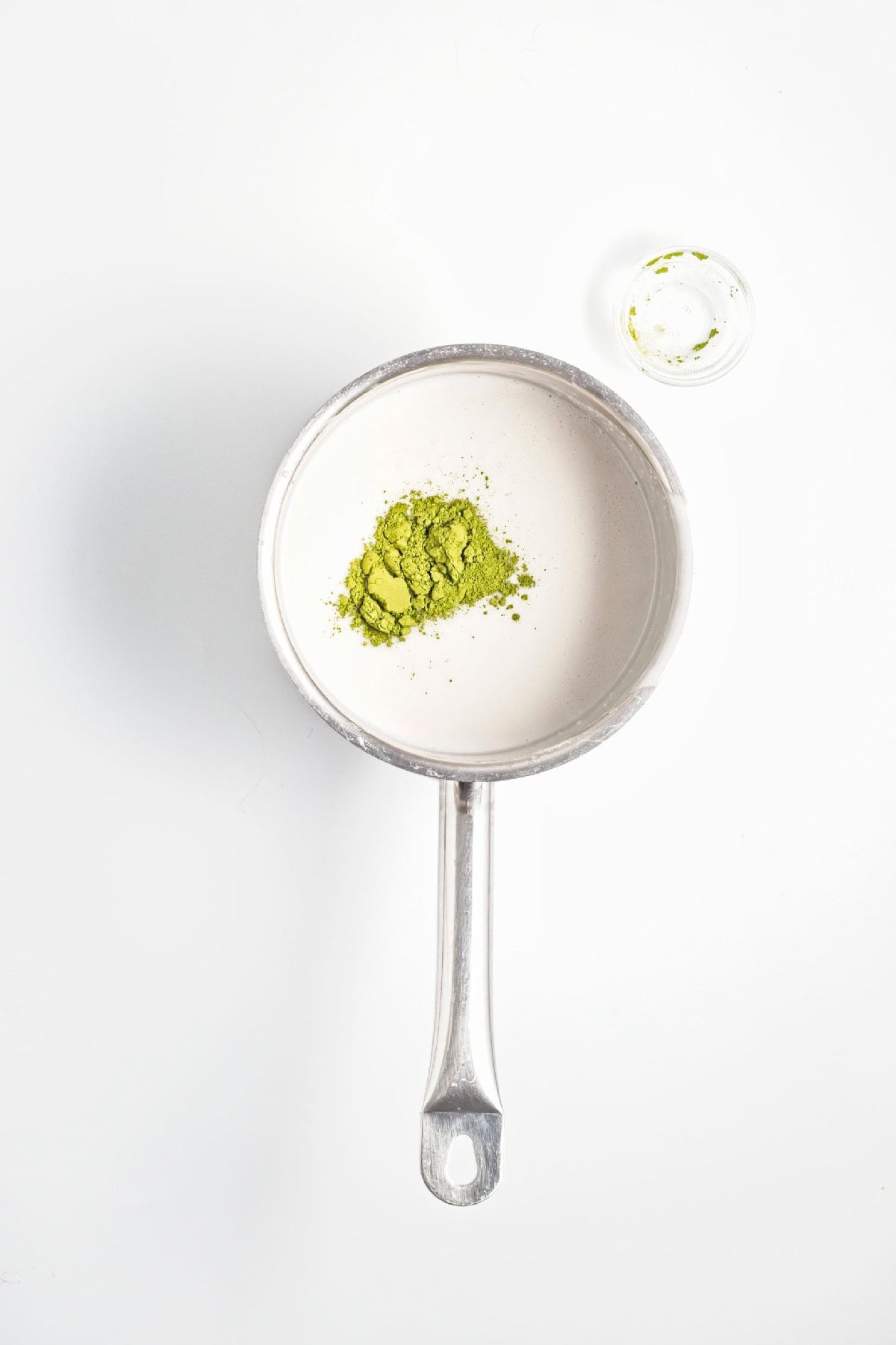 Matcha powder added to the coconut milk mixture in a saucepan.