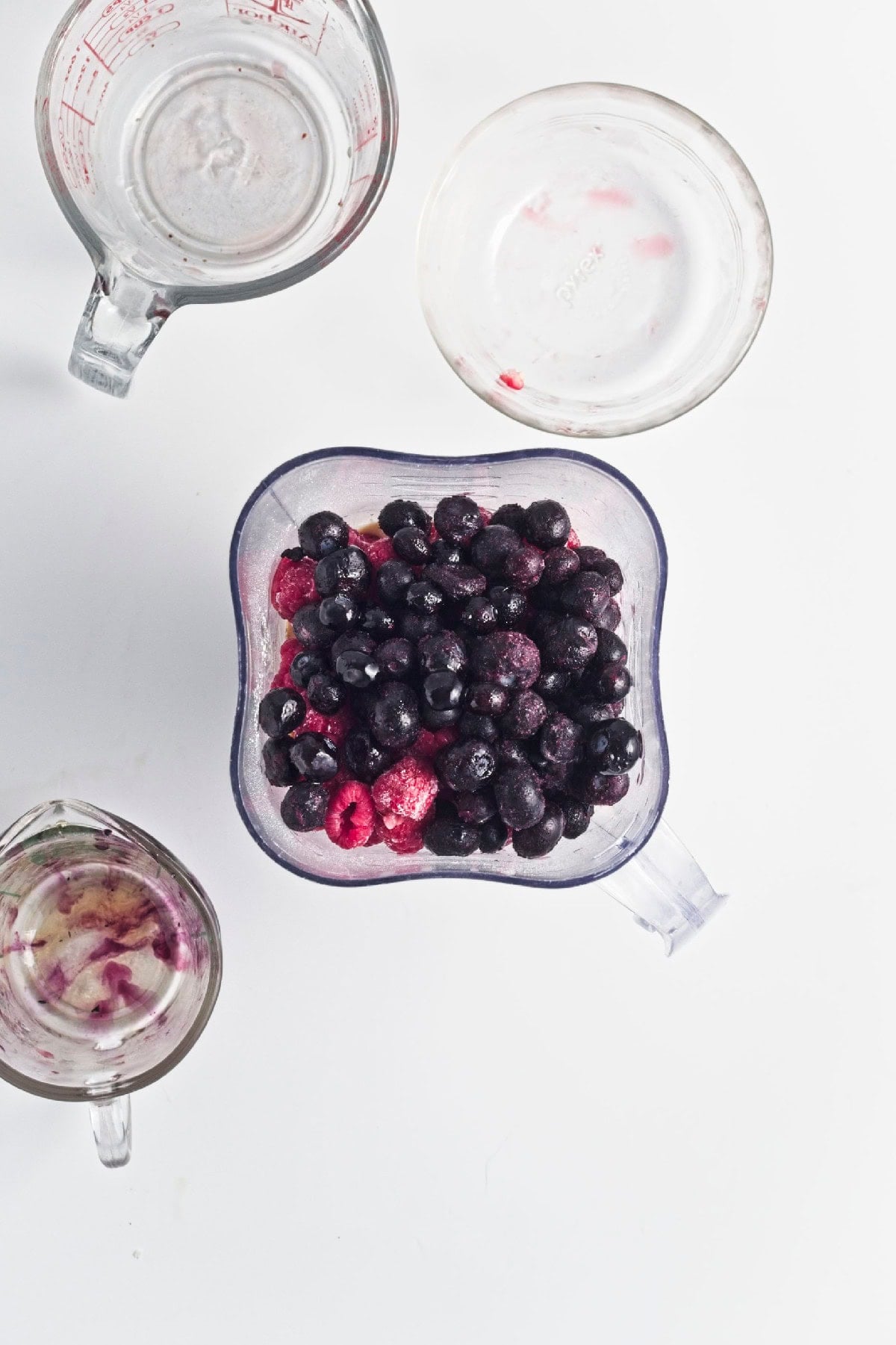 Frozen blueberries and raspberries added to the blender with the smoothie ingredients.
