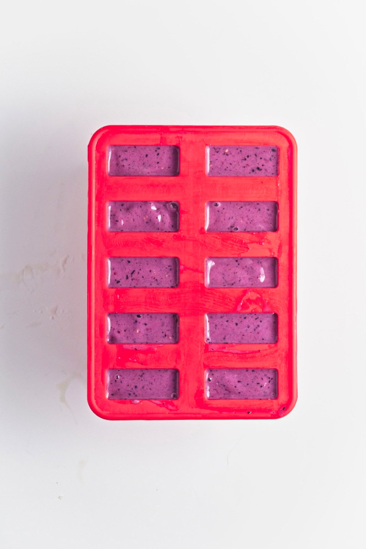 Triple berry smoothie mixture poured into a popsicle mold before freezing.