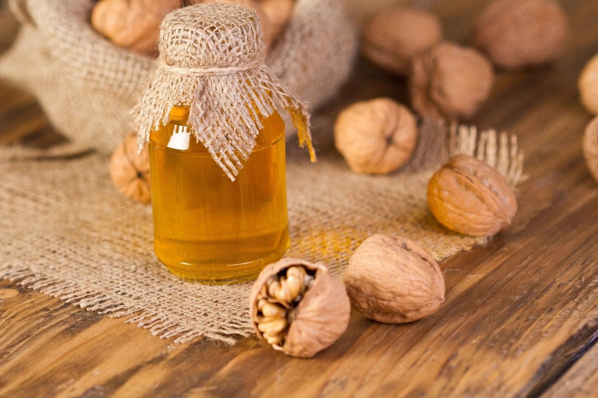 Walnut oil in a glass bottle with whole walnuts, a flavorful sesame oil substitute.
