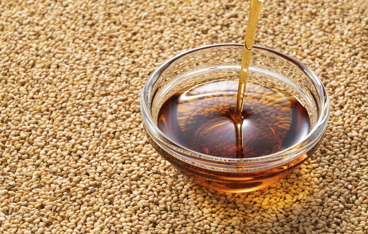 Sesame seeds with toasted sesame oil in a glass bowl for rich, nutty flavor in recipes.