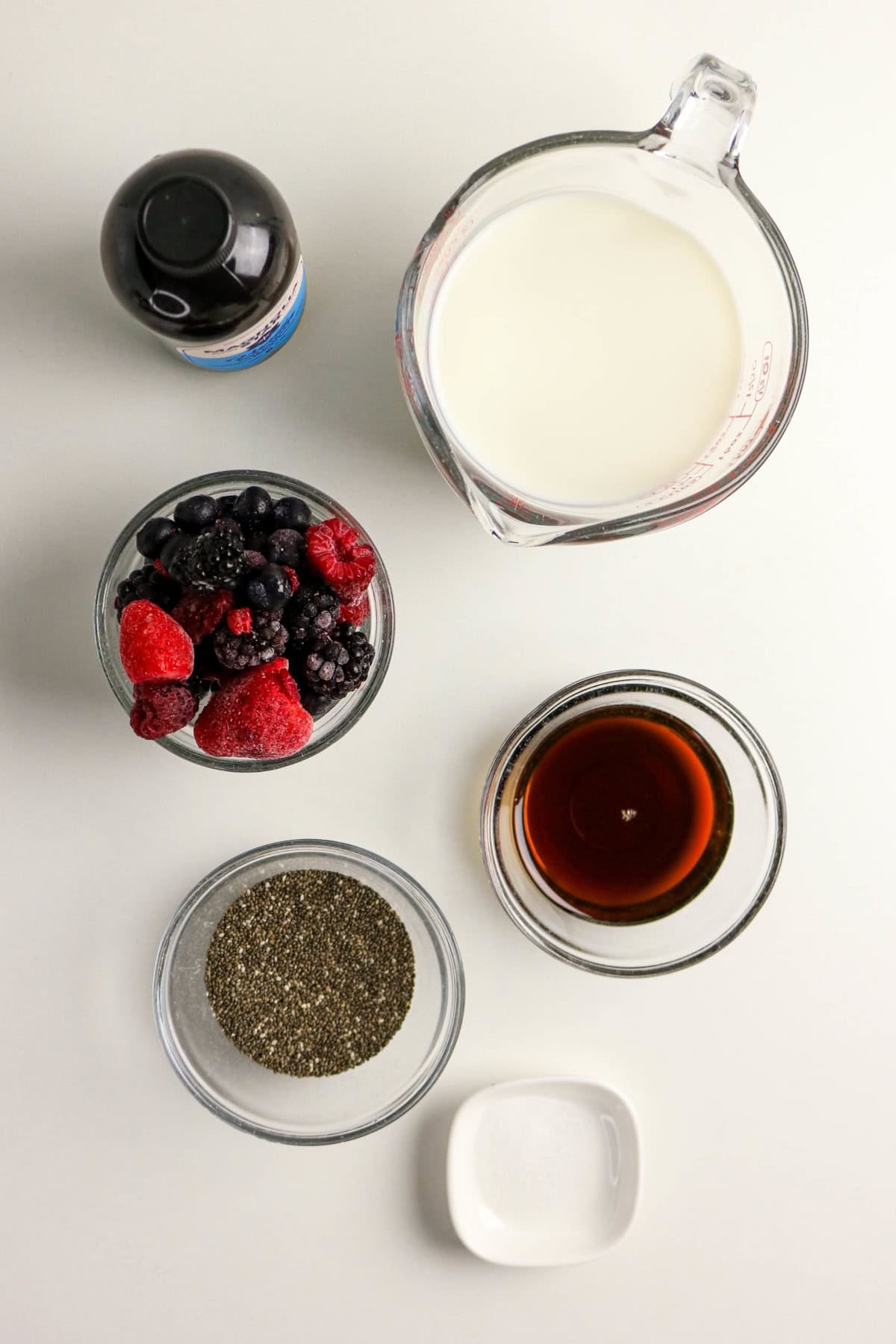 Milk, mixed berries, chia seeds, maple syrup, vanilla extract, and salt for berry chia pudding.
