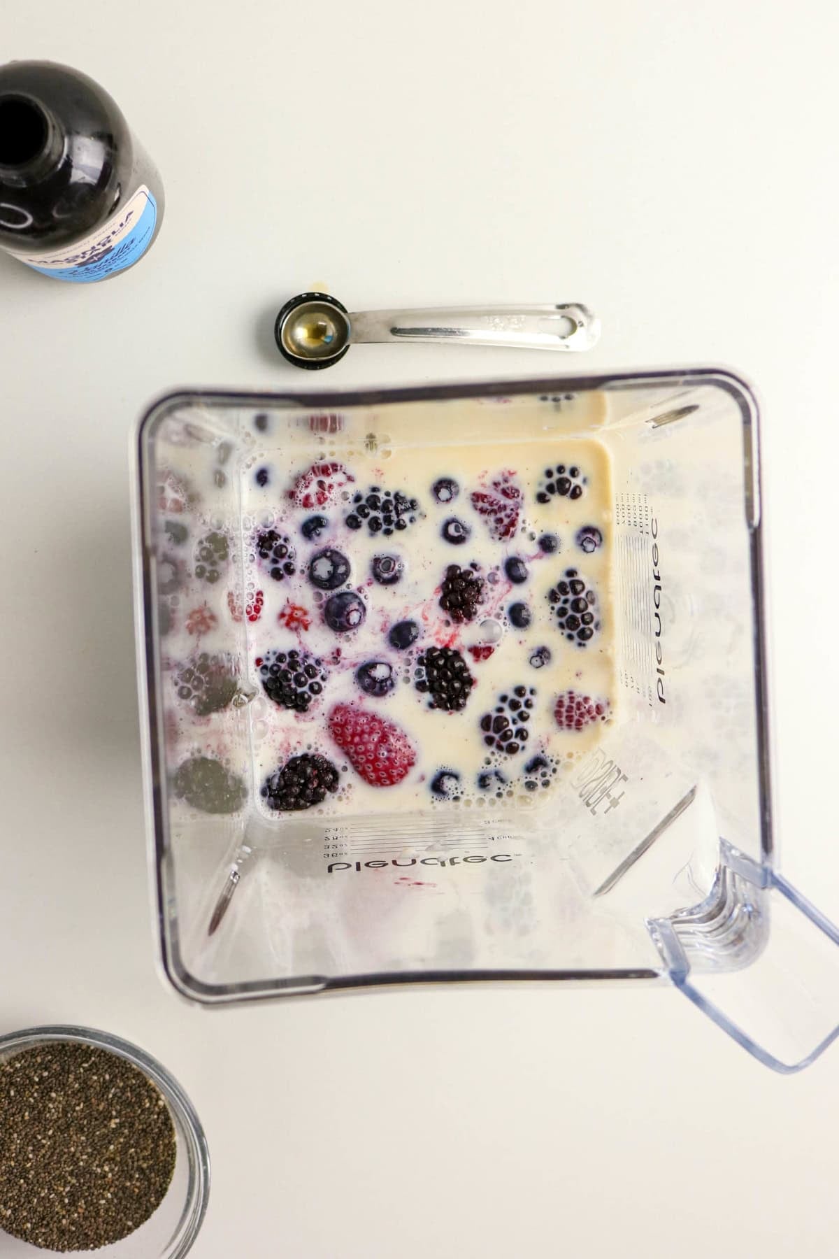 Mixed berries added to the milk mixture in a blender.