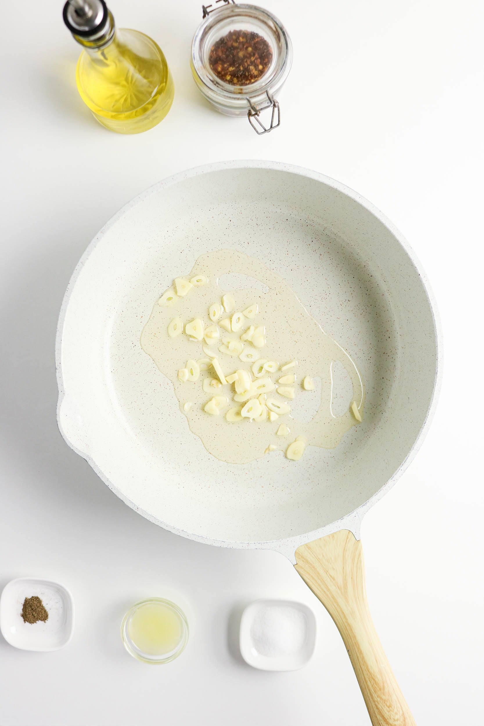 Sliced garlic cooking in olive oil in a skillet.