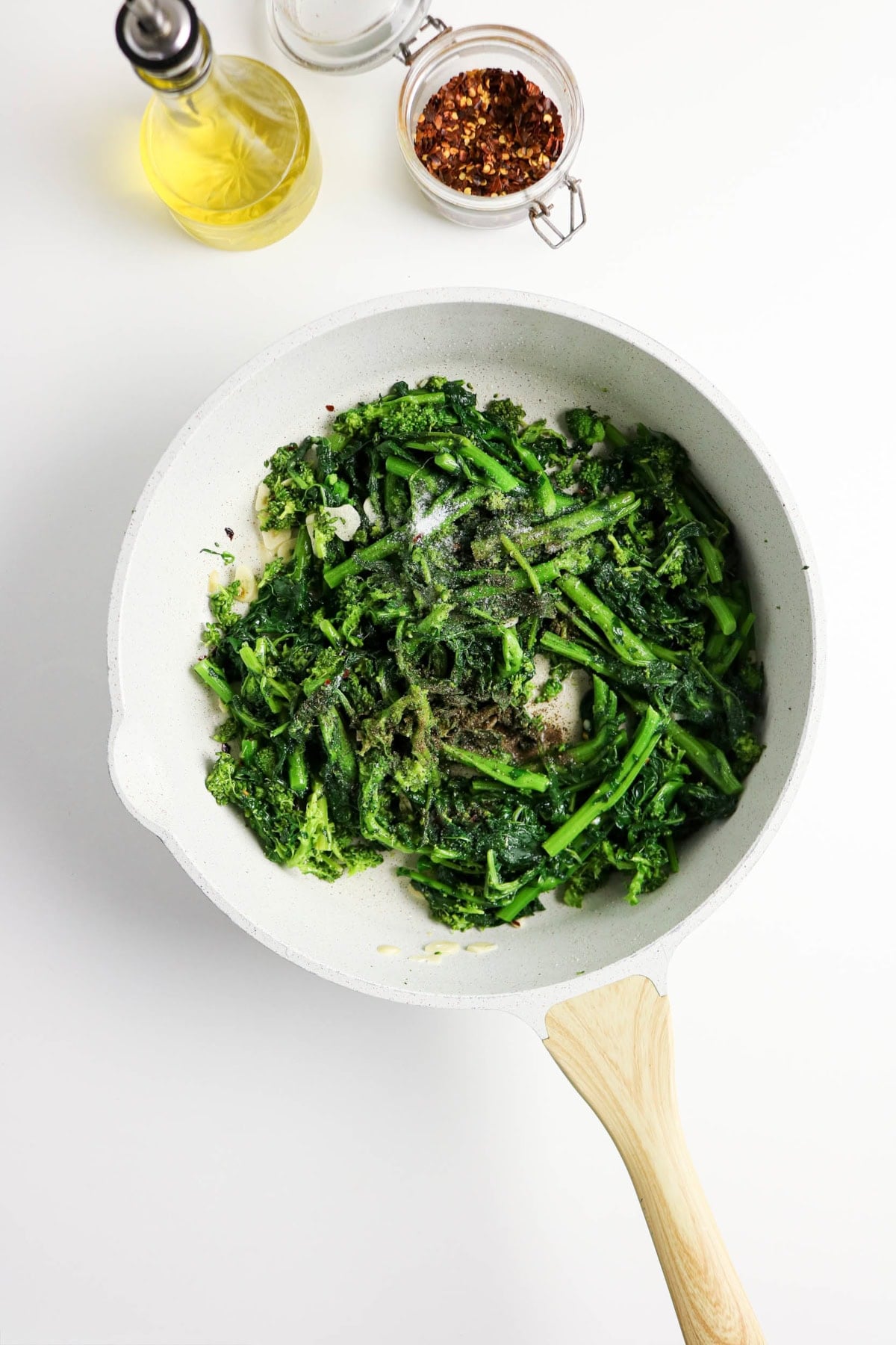 Sautéed rapini seasoned with salt and black pepper in a skillet.