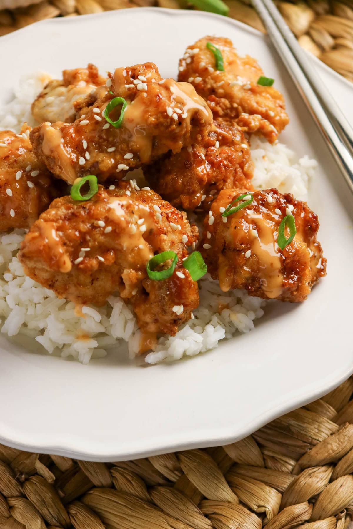 Crispy bang bang chicken with creamy sauce, sesame seeds, and green onions served over white rice.
