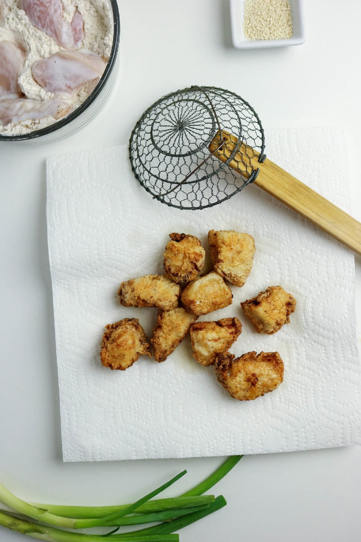 Fried chicken pieces draining on a paper towel.