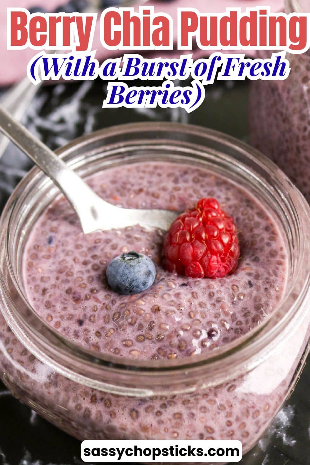 Berry chia pudding in a glass jar topped with a raspberry and blueberry.