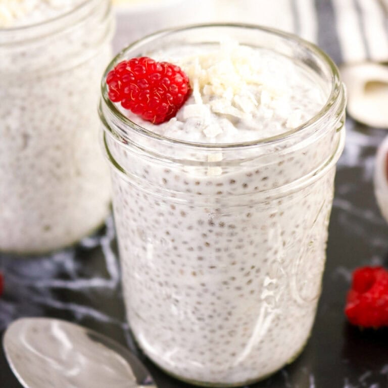 Creamy chia seed and coconut milk pudding topped with shredded coconut and a fresh raspberry.