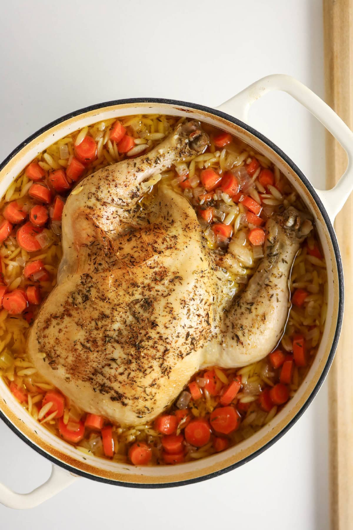 Cooked whole chicken resting on a cutting board before shredding.