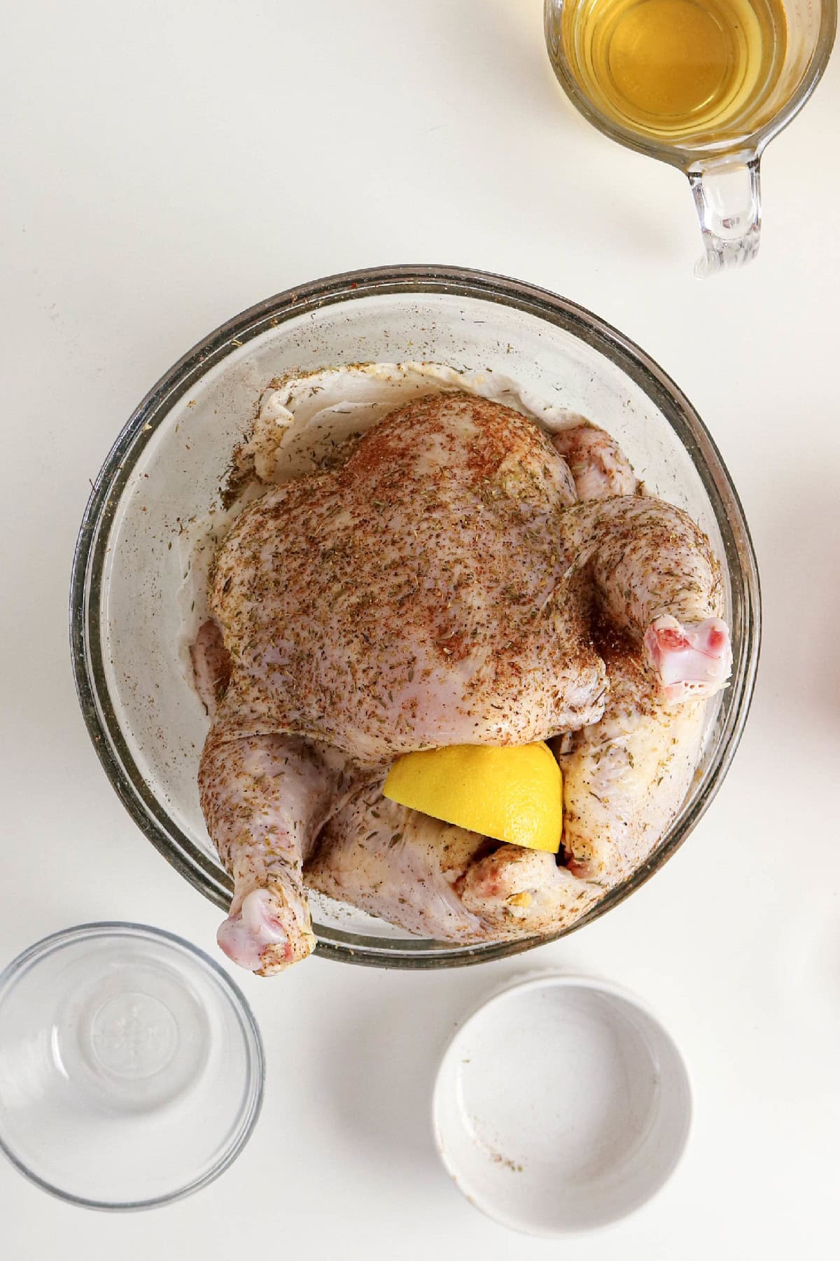 Whole chicken coated with herbs and seasonings with lemon before cooking.