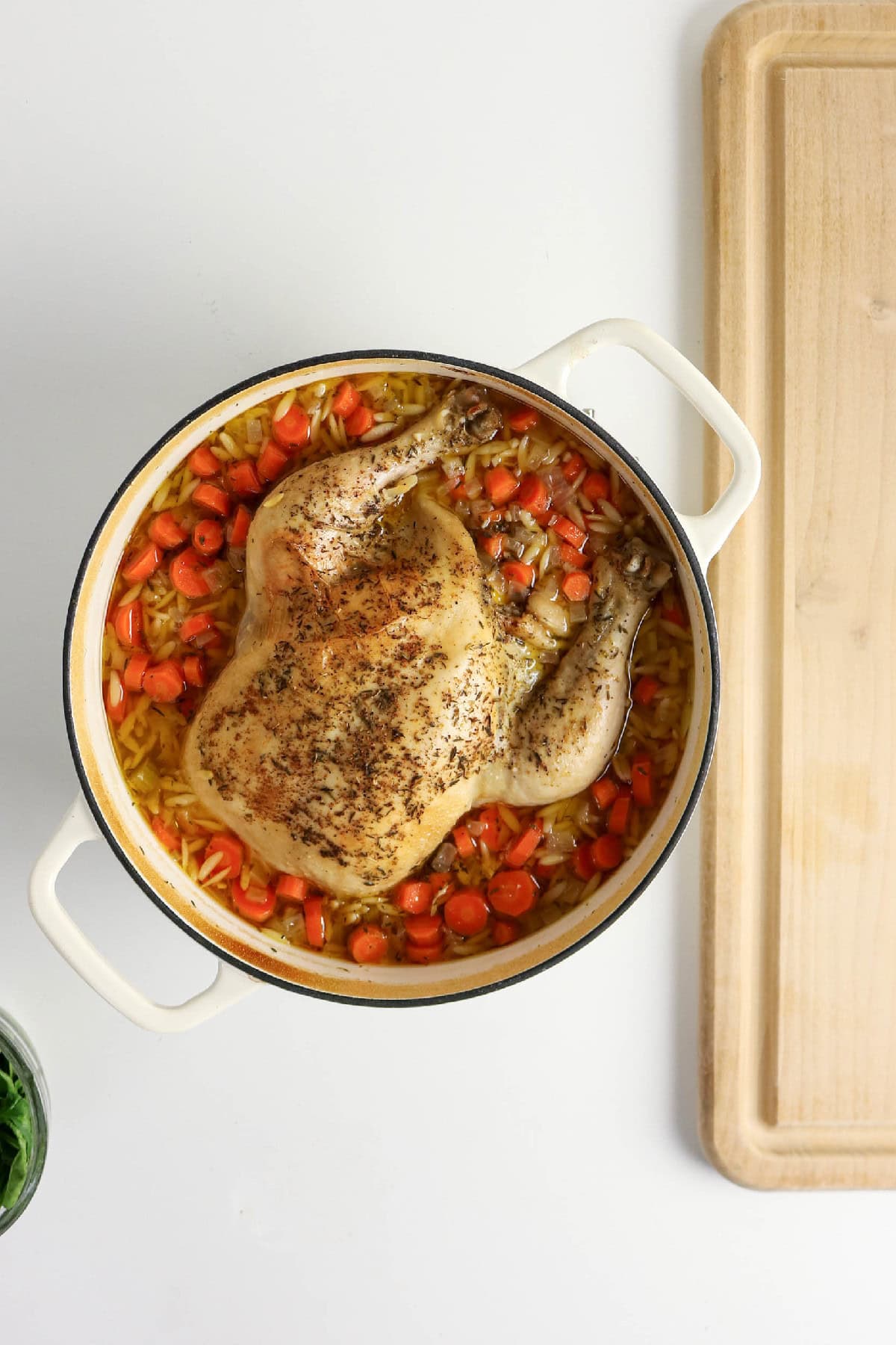 Cooked chicken with orzo, carrots, and broth ready to be removed from the pot.