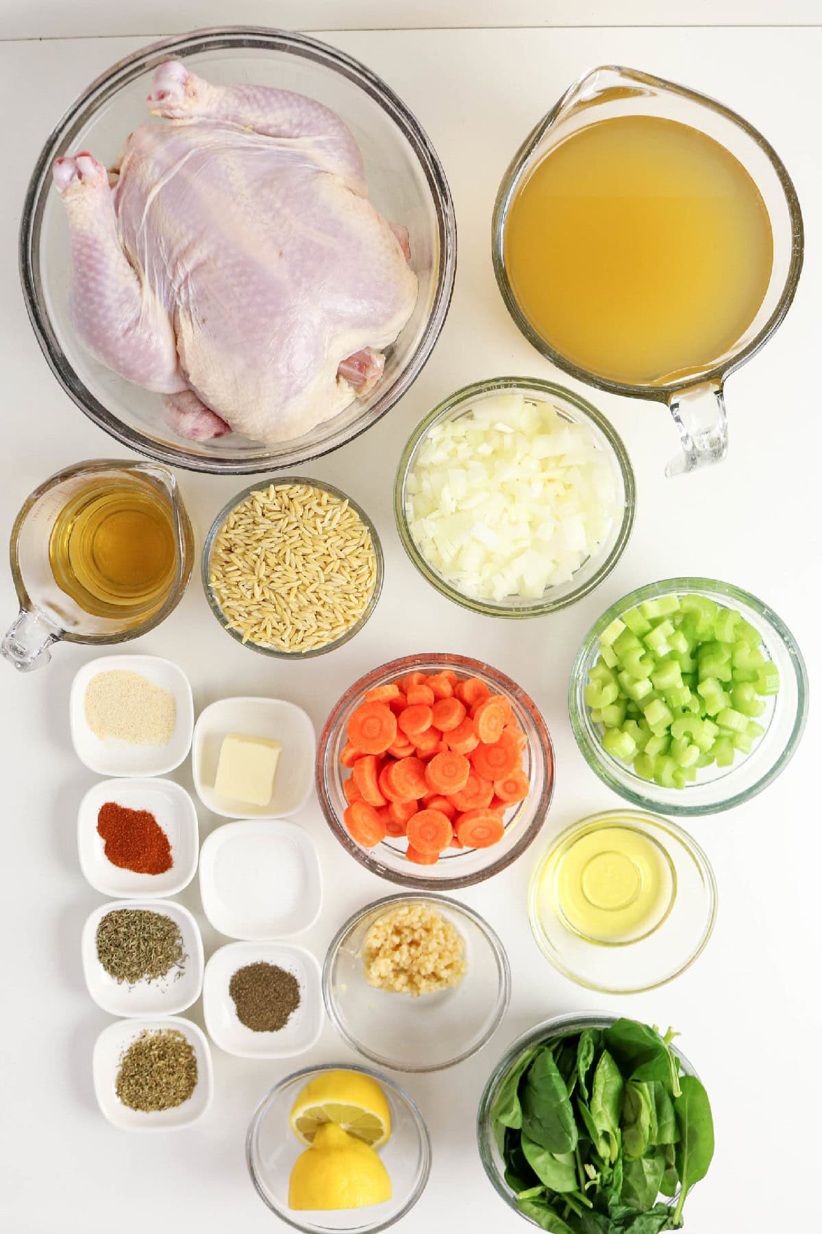 Ingredients for chicken and orzo soup including whole chicken, orzo, broth, carrots, celery, onion, spinach, lemon, garlic, and seasonings.