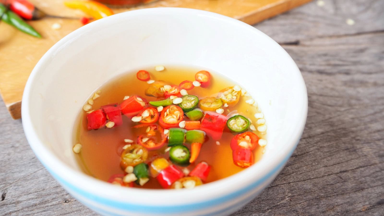 Bowl of fish sauce with sliced red and green chilies.