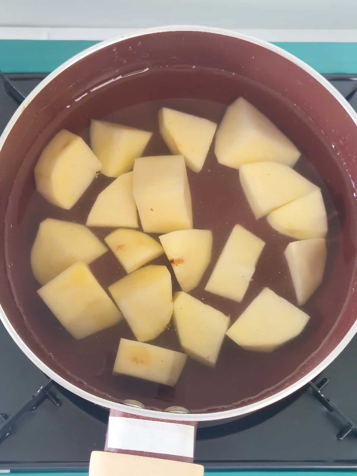 Potato chunks submerged in water in a pot before boiling.