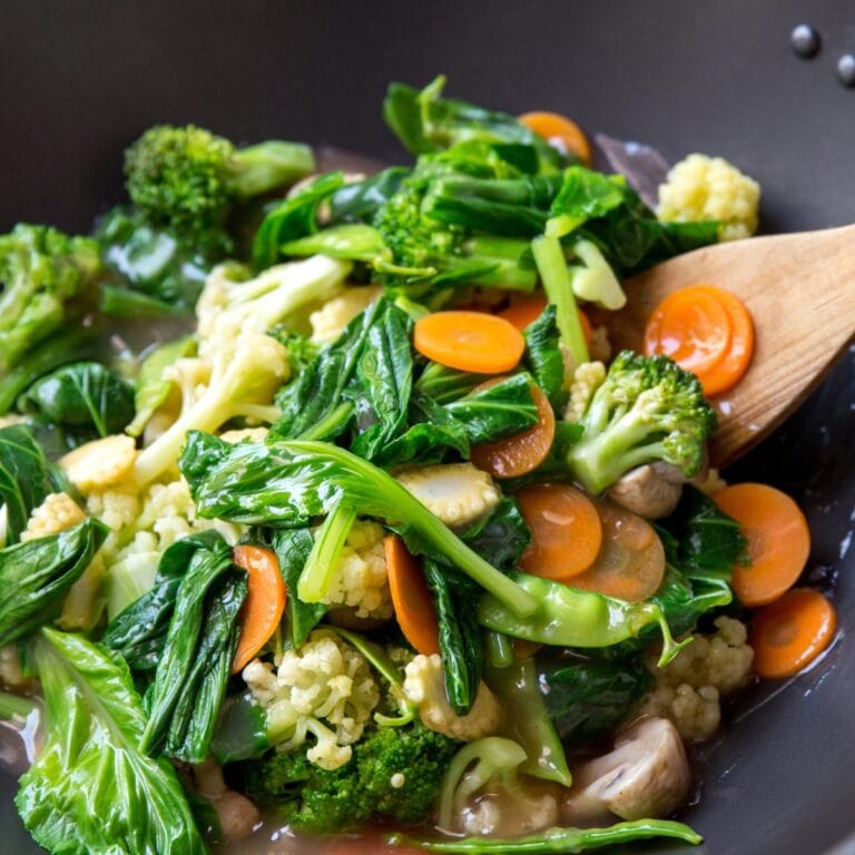 Stir-fried broccoli, snap peas, squash, and assorted vegetables cooked in a wok.