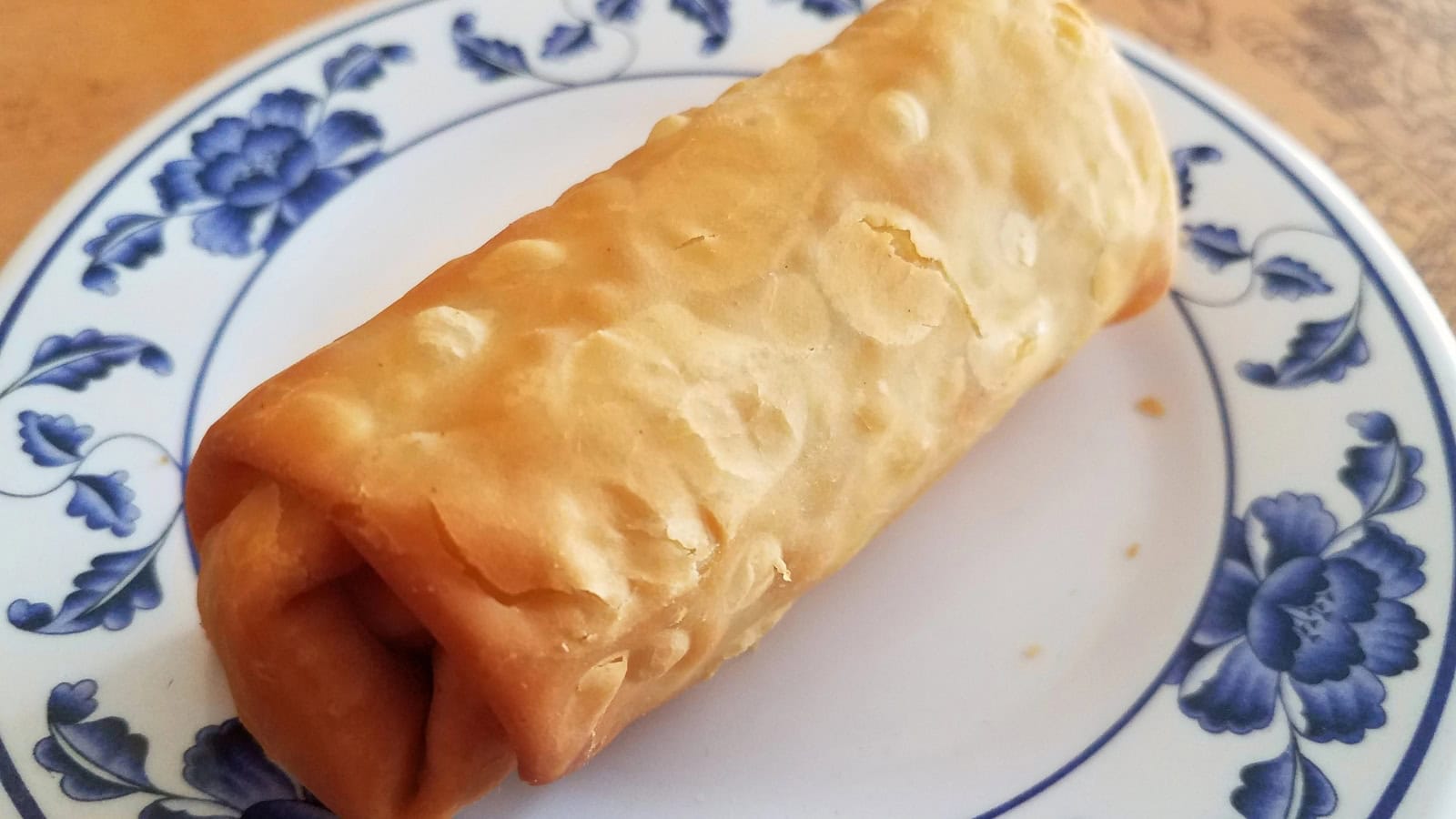 A crispy fried lumpia on a decorative plate.