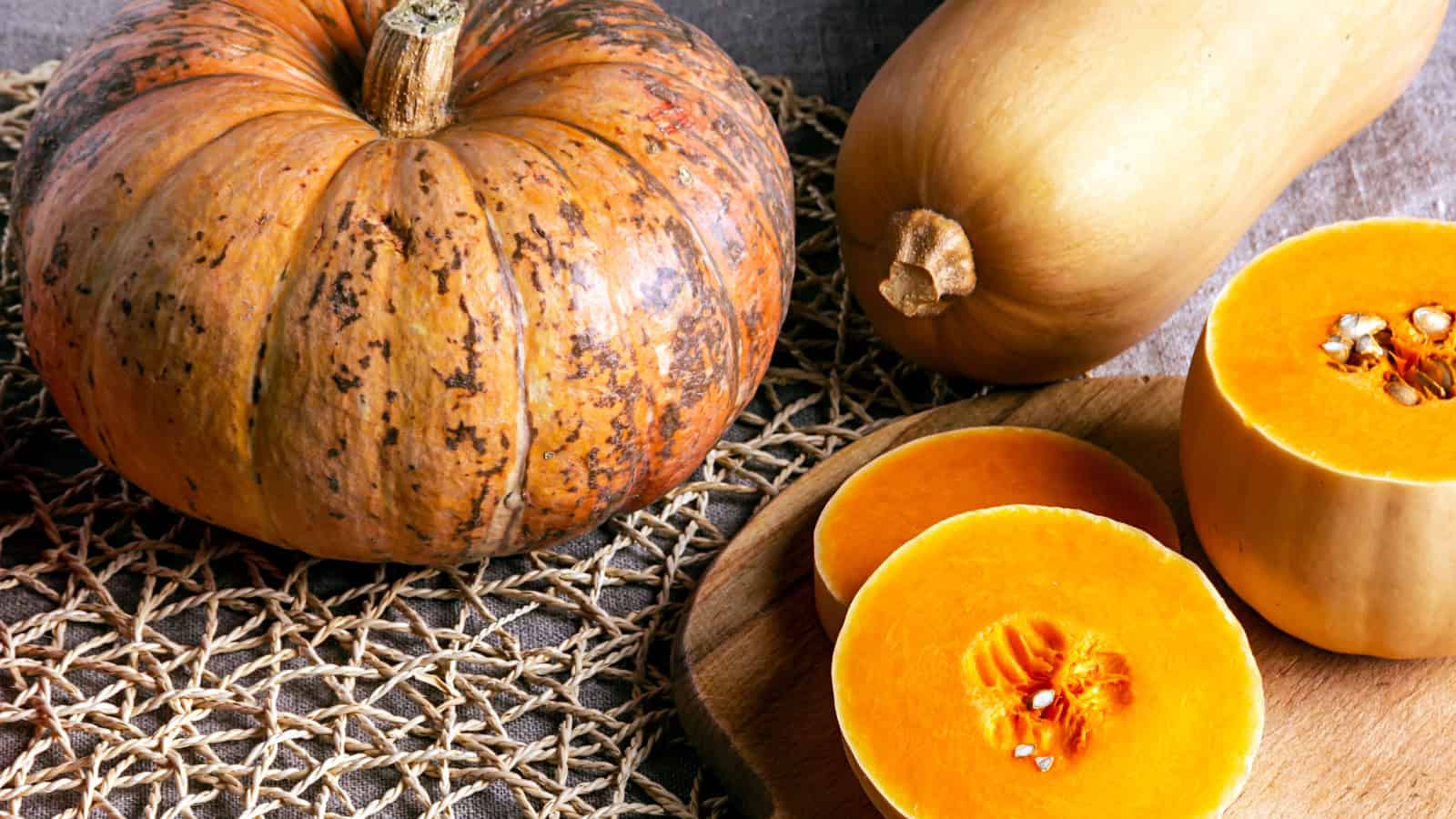 Pumpkin halves and whole pumpkins arranged on a rustic wooden board.