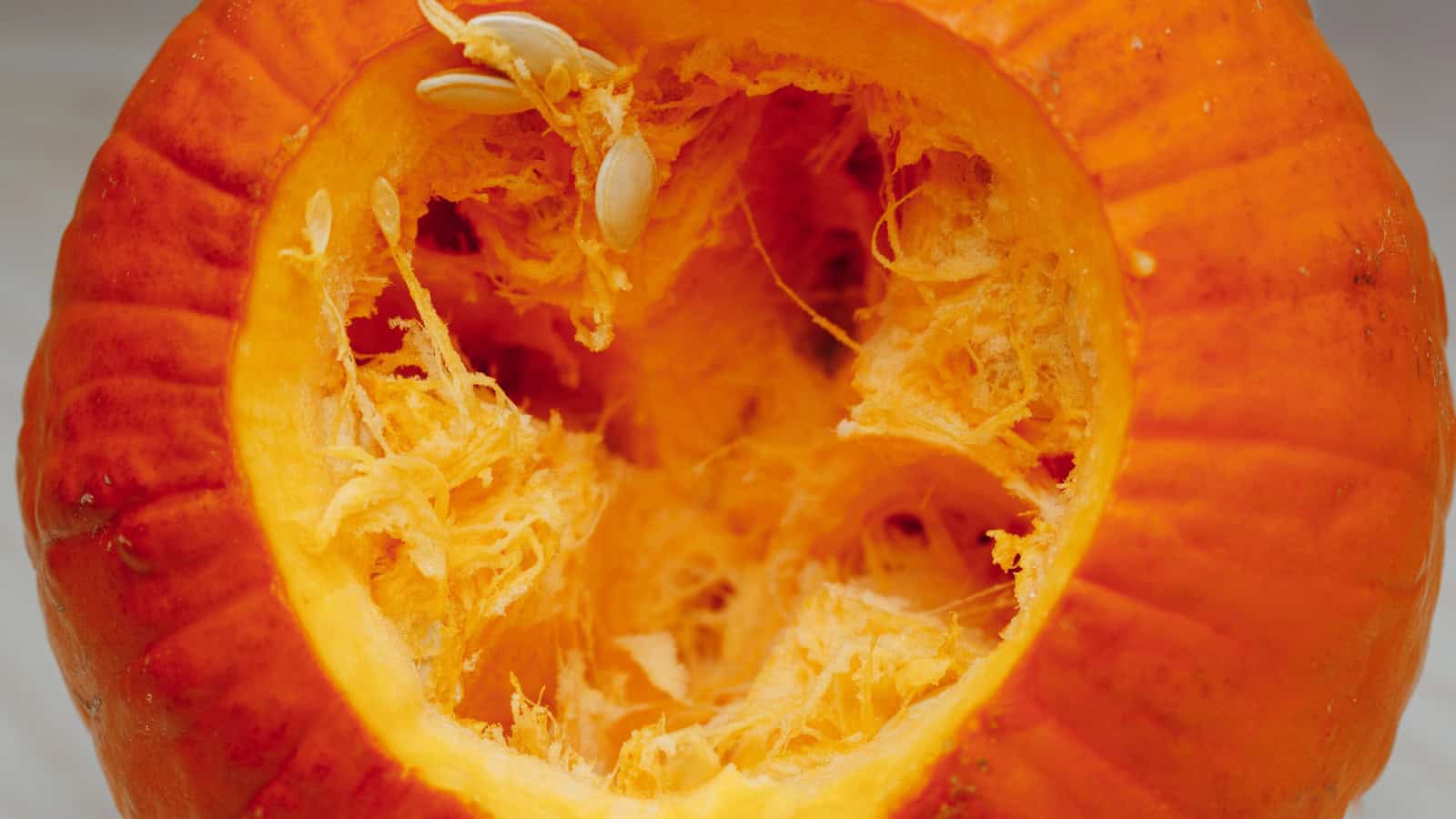 Open pumpkin showing its orange flesh, fibrous interior, and seeds.